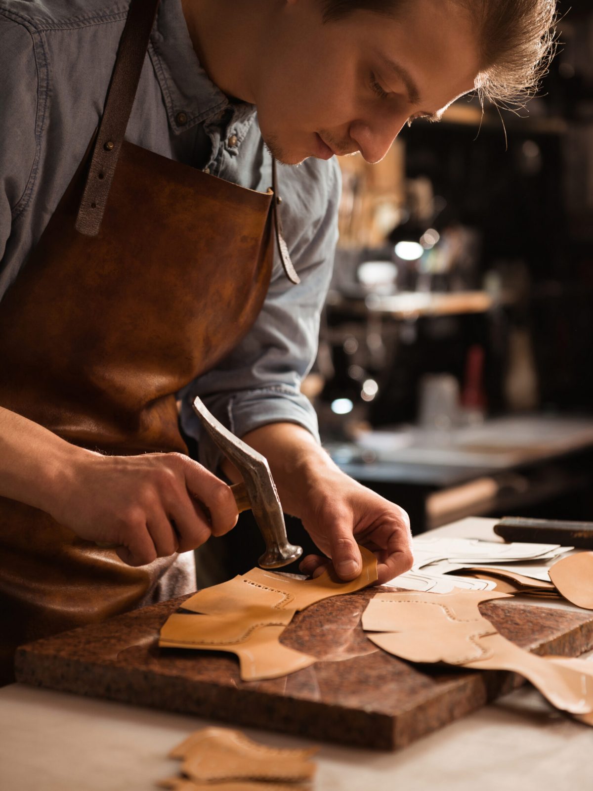 Close up of a shoemaker man working with leather using crafting tools